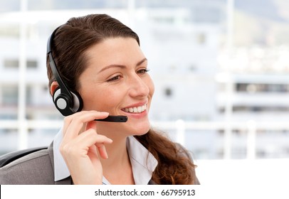 Pretty businesswoman with earpiece sitting in her office