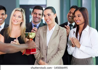 pretty businesswoman and team receiving a trophy