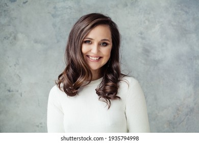Pretty casual woman in white sweater smiling on gray background, portrait