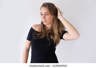 Pretty Caucasian Girl Holding Hand Behind Head And Brushing Hair With Fingers. Young Woman In Black Dress Checking Her Appearance. Mirror Concept