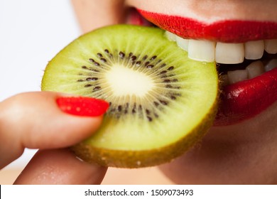 Pretty Caucasian Woman Biting A Slice Of Kiwi, Attractive Red Lips Biting Into A Kiwi Fruit, Smiling With Joy