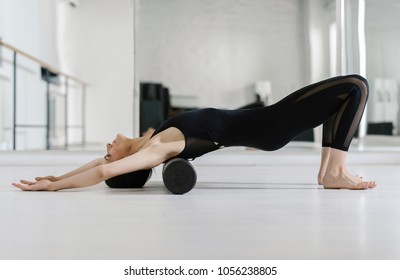 Pretty Caucasian woman doing pilates exercise on the floor with roller.