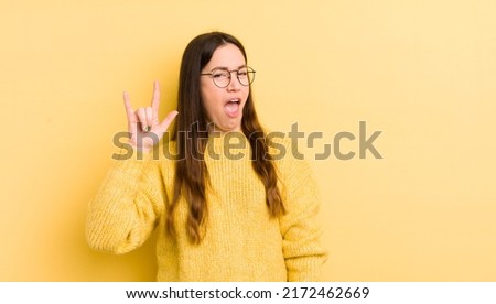 pretty caucasian woman feeling happy, fun, confident, positive and rebellious, making rock or heavy metal sign with hand