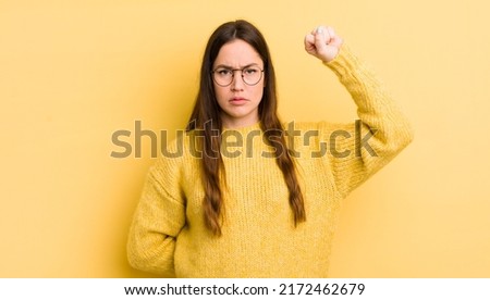 pretty caucasian woman feeling serious, strong and rebellious, raising fist up, protesting or fighting for revolution