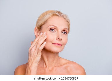 Pretty, charming, attractive woman touching, enjoying her perfect face skin, holding fingers on cheek, pimple, whelk, pustule, dry, oiled, problem skin concept, isolated on grey background