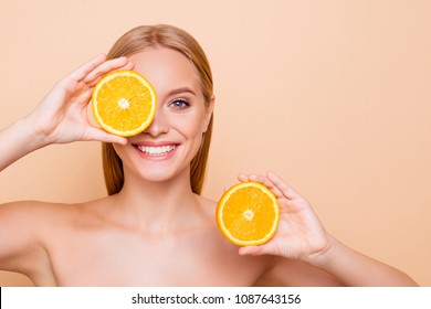 Pretty charming joyful attractive cheerful funny comic positive nude natural pure girl having two pieces of orange, closing one eye, isolated on beige background with copy space for advertisement