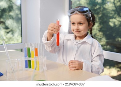 Pretty child chemist, scientist, Caucasian preschooler little girl wearing safety goggles and lab coat doing chemistry experiments, watching the fascinating chemical reaction in the test tube. - Powered by Shutterstock