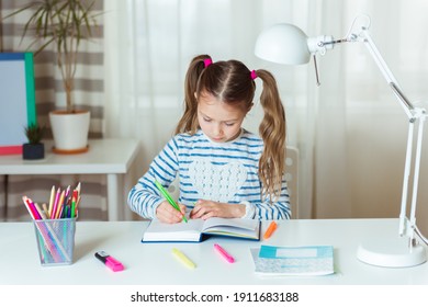 Pretty child girl writing notes in notebook daily planner, planning week, working or studying at home
