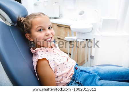 Pretty child with a perfect healthy smile, sitting in the dentist's chair. My teeth is healthy. Children's teeth treatment.