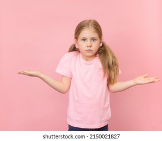 Pretty Clueless Girl Shrugging Shoulders Gesturing I Don't Know. Pussled Child On Pink Background Portrait.