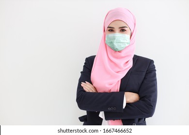Pretty And Confident Muslim Young Asian Woman Wearing Blue Suit With Medical Protective Face Mask To Protect Infection From Coronavirus In Studio On Isolated White Background Portrait. Covid19 Concept
