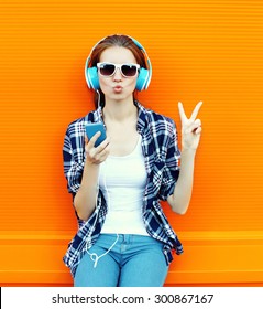 Pretty Cool Girl Having Fun And Listens To Music In The Headphones On Smartphone Over Colorful Background