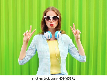 Pretty Cool Woman Listens To Music In Headphones Over Green Background