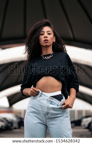 Similar – Young woman with curly hair near a modern colorful building