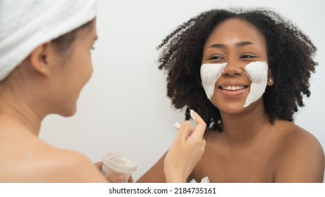 Pretty couple Asian African woman friend smile and fun together with masking face spa cosmetic as diversity racial LGBT - Powered by Shutterstock