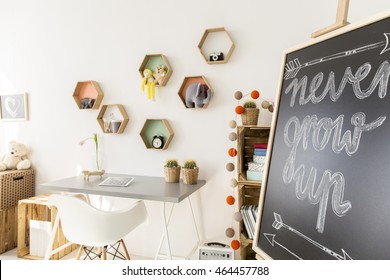 Pretty Cozy White Children's Room With Hexagon Shape Shelves Above The Desk. Next To It Blackboard With Sign