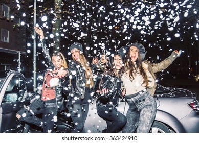 Pretty crazy girls dancing, throwing confetti and drinking wine - Young women partying outdoors before to go in a club