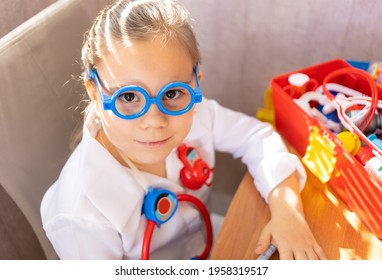 Pretty Cute Preschool Child Girl Wearing In White Medical Uniform Playing With Sick Teddy Bear Toy As Patient In Hospital Game