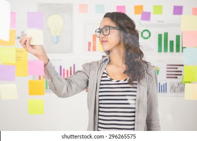 Pretty Designer Looking At Post Its On Window In The Office