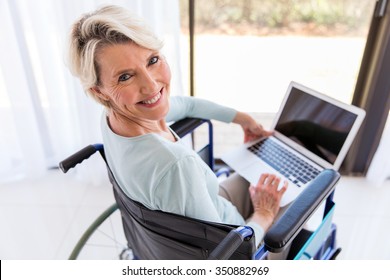 Pretty Disabled Middle Aged Woman With Laptop Computer At Home