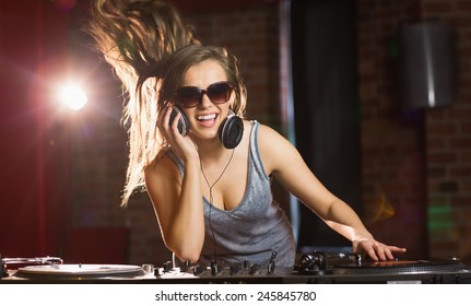 Pretty dj smiling and dancing at the nightclub