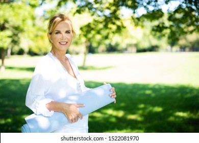 Pretty Elderly Woman With Yoga Mat In The Park