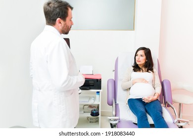 Pretty expectant mother talking with a male gynecologist. Pregnant woman listening to her doctor while lying on the examination chair 