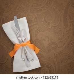 Pretty And Fancy Fall Place Setting With Silverware, Orange Ribbon Napkin Ring And Brown Patterned Tablecloth With Room Or Space For Your Words, Text, Or Copy.  Square Crop With Flat Lay Above View