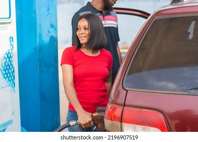 Pretty Female African Petrol Station Attendant Filling Up A Car