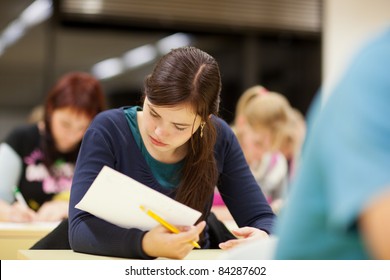 pretty female college student sitting in a classroom full of students during class (shallow DOF; color toned image)