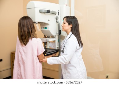 Pretty female doctor setting a patient in the correct position to get a mammogram in a clinic