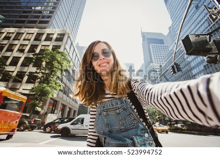 Pretty female girl tourist smiling and taking selfie in Manhattan, New York. Beautiful young photographer takes pictures for her travel blog.