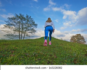 Pretty female going up the hill to clouds with a nice background