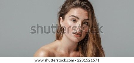 Pretty female model with natural freckled face and shoulder. Beauty woman looking a the camera. Healthy skin concept. Studio shot. 
