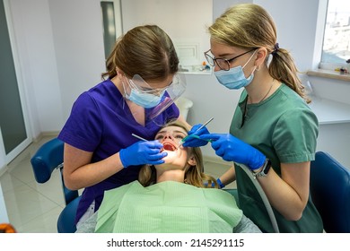 Pretty female patient sitting in armchair while doctor with assistant examining her teeth. Stomatology concept - Shutterstock ID 2145291115