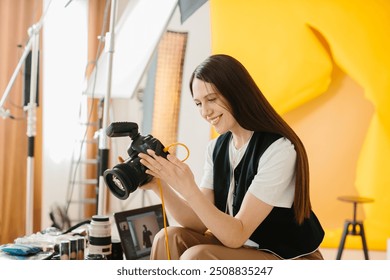 A pretty female photographer with a professional camera sits on her desk and looks at the pictures after a photo shoot. - Powered by Shutterstock