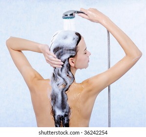 Pretty female standing back and washing her long hair