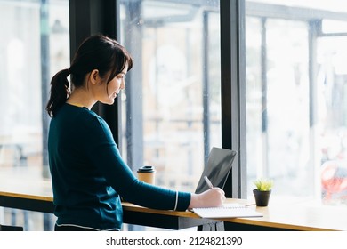 Pretty Female Student With Cute Smile Keyboarding Something On Laptop While Relaxing After Lectures In University, Beautiful Happy Woman Working On Laptop Computer During Coffee Break In Cafe Bar.