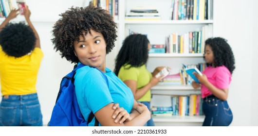 Pretty Female Student With Group Of African American College Students Indoors At Library