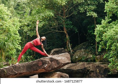 Pretty Fit Black Woman Doing Triangle Pose On Big Rock In The Forest