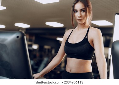 Pretty fit woman in black sportrswear training on a treadmill
