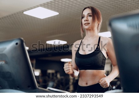 Pretty fit woman in black sportrswear training on a treadmill