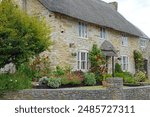 Pretty Flowered Garden Surrounding An English Thatched Cottage.                      