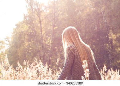 Pretty Fresh Blonde Young Woman Walking Outdoors In The Sun And High Grass And Wearing A Coat