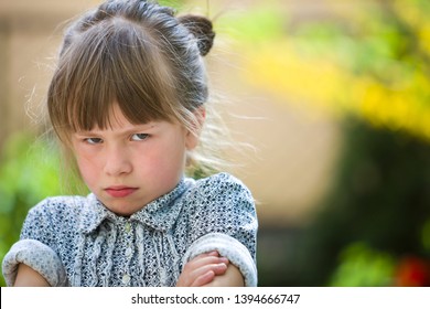 Pretty Funny Moody Young Child Girl Outdoor Feeling Angry And Unsatisfied On Blurred Summer Green Background. Children Tantrum Concept.