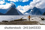 pretty girl admiring the unique scenery of famous milford sound, fiordlands national park, new zealand south island