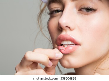 Pretty girl or beautiful woman, young, cute, sexy, fashion model piercing lip with ring on grey background