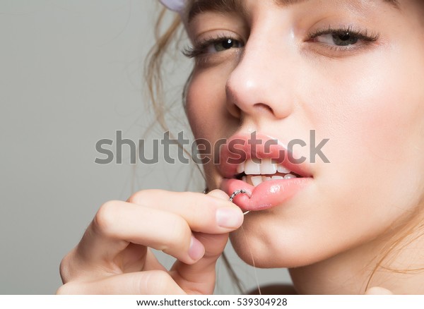Pretty girl or beautiful\
woman, young, cute, sexy, fashion model piercing lip with ring on\
grey background