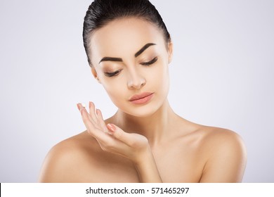 Pretty girl with black fixed hair behind, soft skin and naked shoulders using cream, a model with light nude make-up, portrait, beauty photo. - Shutterstock ID 571465297