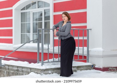 A Pretty Girl In A Cardigan, Stands At The Porch Of The House In Winter, The Model Poses On The Street